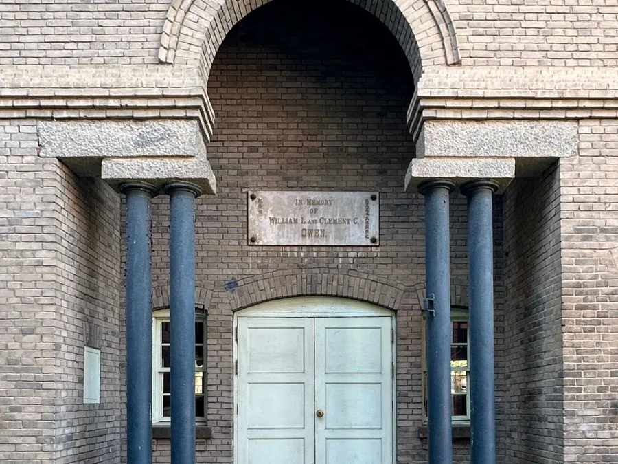 The arched brick entrance of Owen Memorial Hall, the stone plaque set between its columns