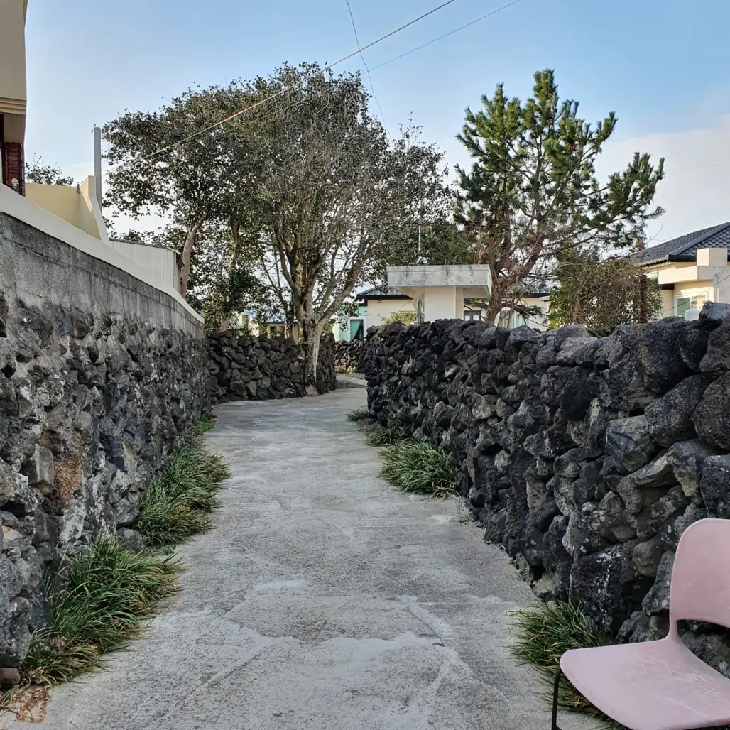 A narrow lane running between stone walls towards the houses behind