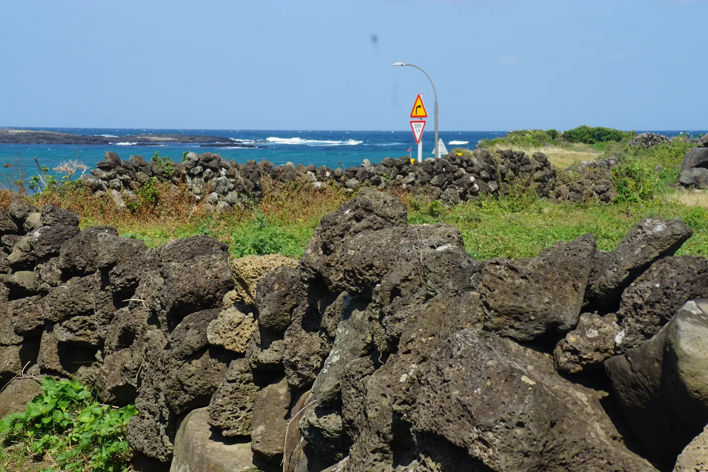 Black basalt and low stone walls along the shore of U-do