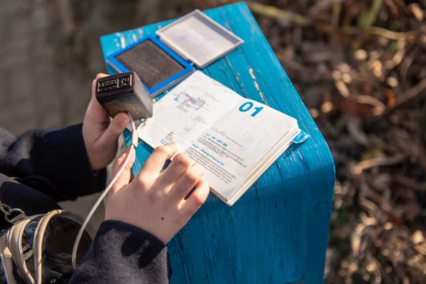 A hand pressing a Ganse stamp into a Jeju Olle passport