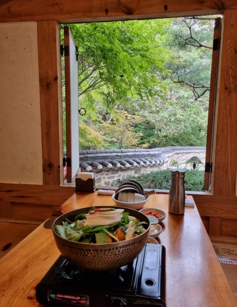 Baeksuk on the table at a hanok restaurant, open window onto the garden