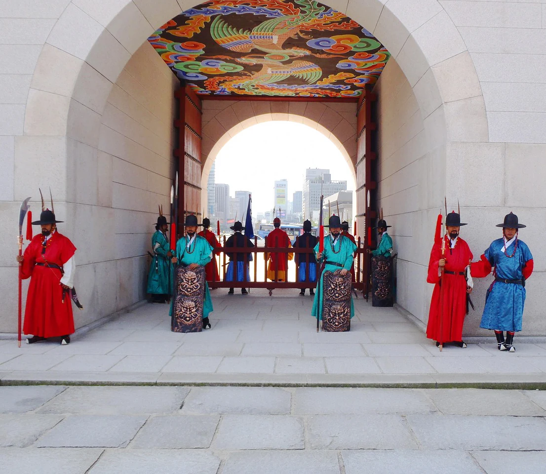 Guards in traditional uniform standing in formation inside a palace gate arch