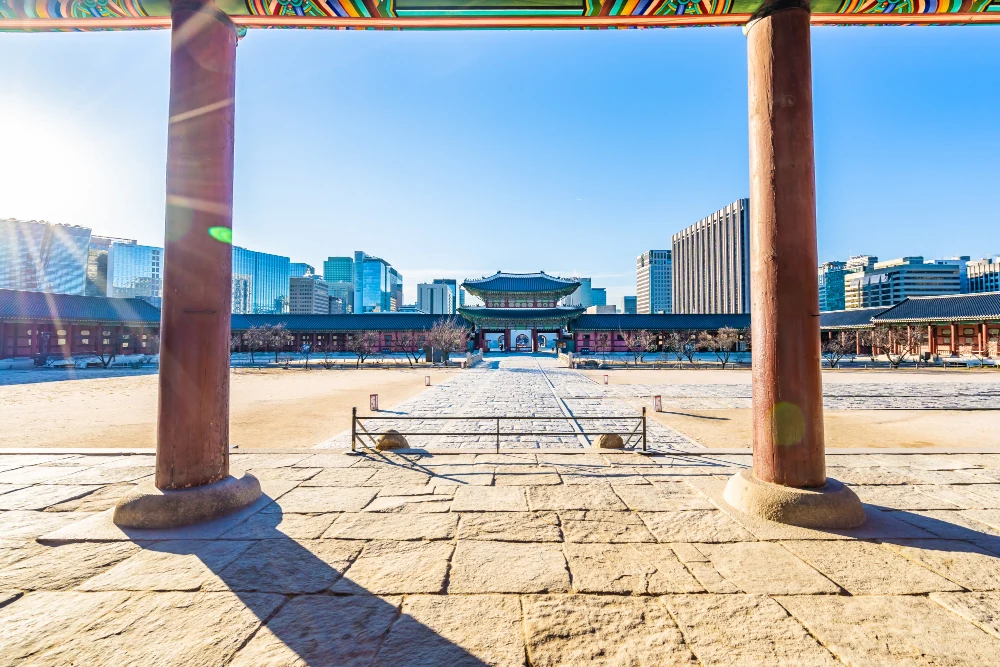 City towers framed between the wooden pillars of a palace gate