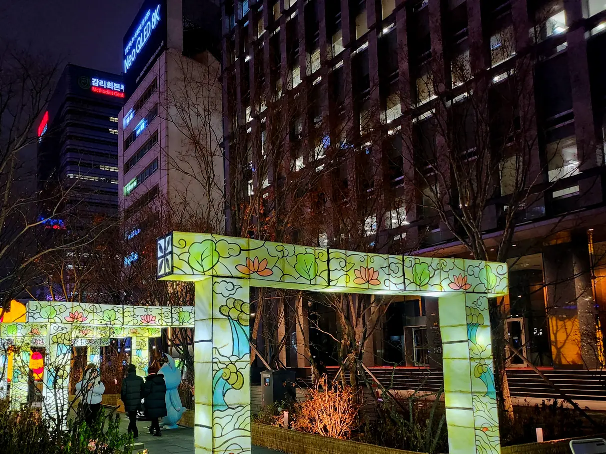 Lit sculpture gateway spanning a night walkway