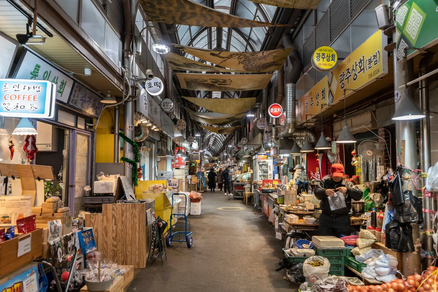 Covered market arcade lined with shops and shoppers walking through