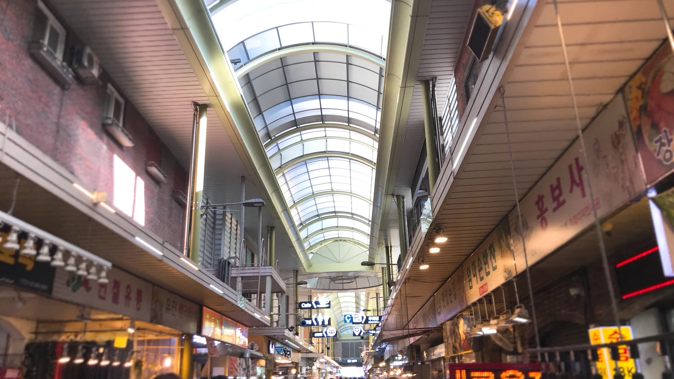 Covered market arcade stretching into the distance under a curved glass roof