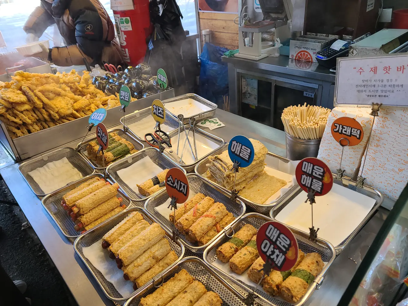 Fish cakes and fried snacks arranged in metal trays with printed name cards