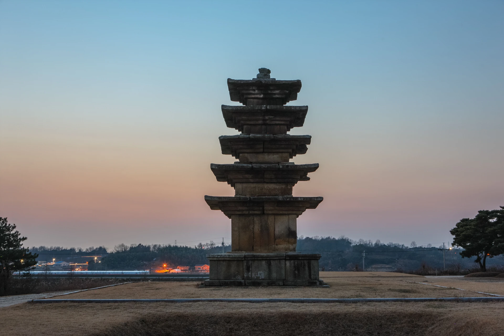 A five-storey stone pagoda standing alone against a dusk sky